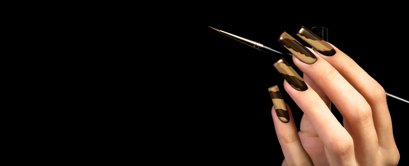 Hand with nail art on nails holding a liner brush